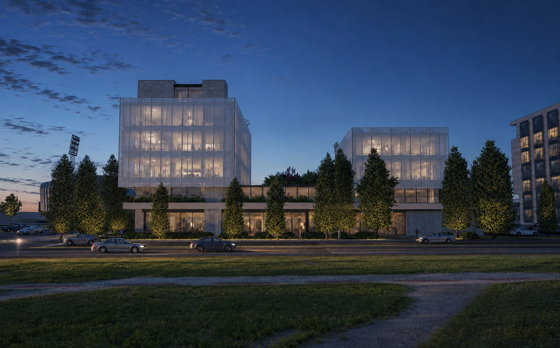 The street facade at night — illuminated volumes and the planted podium